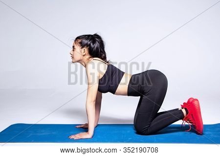 The Beautiful Wearing Exercise Suit,sitty On Mat,show Backside,raise Hands Cross Her Body ,posing Ba