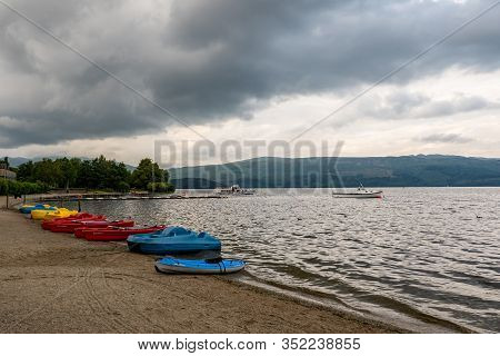 Luss, Scotland - August 1, 2019: Kayaks And Other Boats On A Shore Of The Loch Lomond In Scotland Wi
