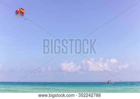 Bright Parachute Pulled By Power Boat On Calm Blue Ocean - Negative Space And Copy Space