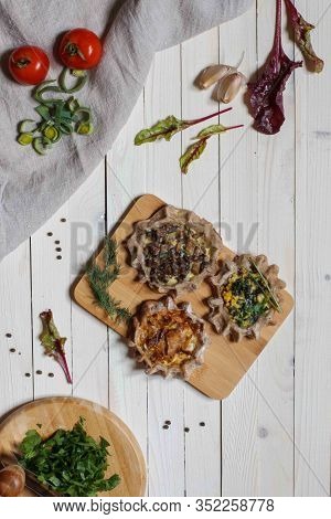 Three Open Small Buckwheat Flour Pies With Vegetarian Fillings On White Boards With Tomatoes And Cho
