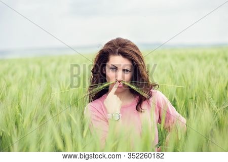 Beautiful, Pretty Young Woman Imitating Upset Suspicious Man. Attractive Girl Holding   Wheat Ear Un