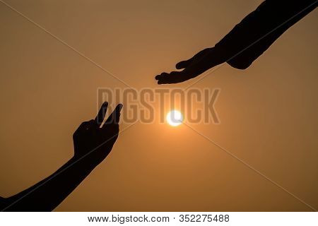 Giving A Helping Hand On The Background Of The Sunset.