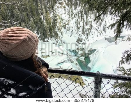 A Young Hiker Looking Down Admiring The Beautiful View Of A Frozen Waterfall At Wapta Falls With The