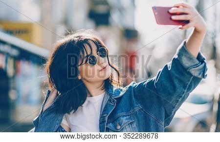 Close Up Portrait Of A Cheerful Lady Making A Selfie While Looking Through Her Sunglasses And Wearin
