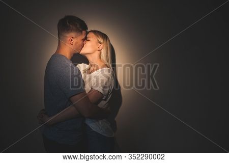 Two Caucasian Lovers Kissing Each Other With A Wall On Background Against A Charming Light