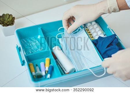 Hand In Gloves Take Protective Midicine Mask From First Aid Kit. Home Medicine Box With A Medical It