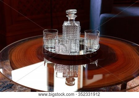 An Empty Decanter For Brandy And Three Square Glasses Are On The Table In The Office.