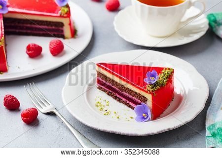 Raspberry Layerd Cake Decorated With Violet Edible Flowers And Tea Cup. Grey Stone Background.