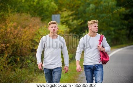 Twins Walk Along Road. Adventure Concept. Guys Hitchhiking On Road. Tourist Traveler Travel Auto Sto