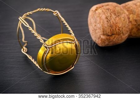 Champagne Muselet With Gold Cap And Cork On Black Stone Background. Close-up