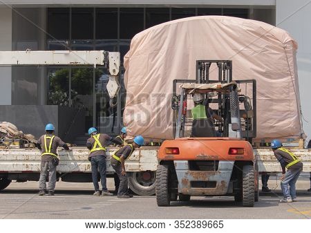 Orange Forklift Is Lifting The Train Head, Covering The Pink Cloth, With The Workers Wearing Work Cl