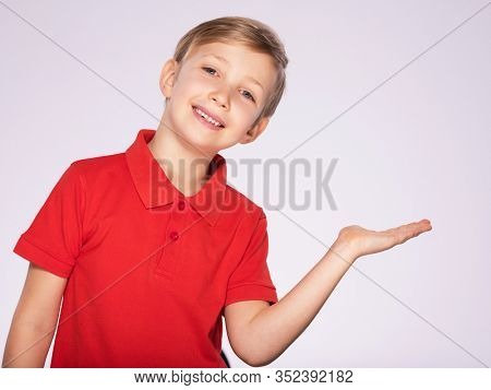 8 year old kid with a empty palm.  Portrait of cheerful boy with a palm turned over up, isolated over white background. Child with an empty palm. Cheerful boy in a red t-shirt shows something 