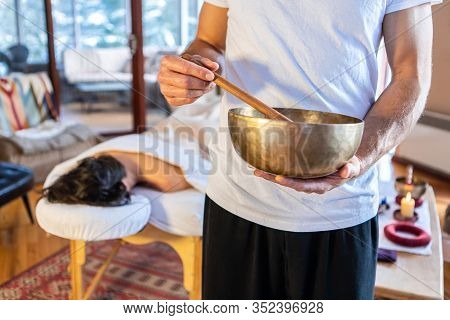 Man Holding A Bronze Sound Bowl With A Stick - Used For Sound Therapy And Sound Massages. A Professi
