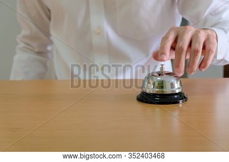Men Wearing White Shirt Reaching His Hand And Finger To Ring A Reception Or Restuarant Bell On Wood 