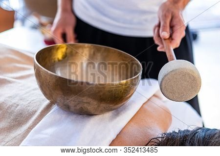 A Masseur Standing With A Tibetan Bronze Sound Bowl With A Stick. A Professional Massage Therapist G