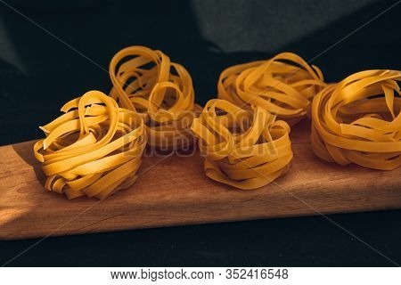 Pasta Alluovo, Tagliatelle Pasta, Round Balls Of Raw Pasta On The Wooden Cutting Board On Black Back