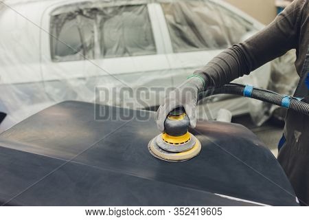 Auto Mechanic Preparing The Car For Paint Job By Applying Polish With The Power Buffer Machine