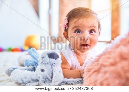 Beautiful infant happy at kindergarten around colorful toys lying on blacket