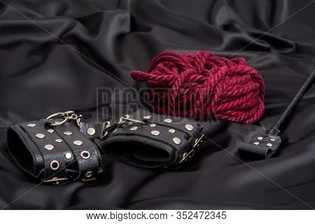 Leather Handcuffs, Shibari Rope And Stack On Black Background