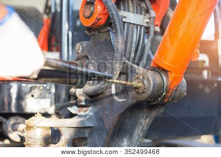 Hand Of A Workman Greasing The Grease Nipple Of A Hydraulic Cylinder The Backhoe. Routine Repair Mai