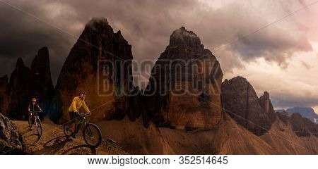 Cycling outdoor adventure in Dolomites. Cycling woman and man  on electric mountain bikes in Dolomites landscape. Couple cycling MTB enduro trail track. Outdoor sport activity.