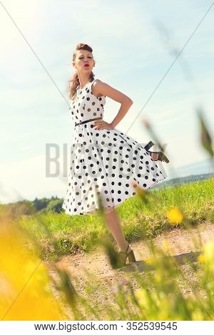 Portrait Of A Rockabilly Girl With A Petticoat Dress And A Suicide Roll On A Nature Path, Backlight