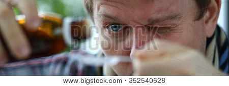 Close-up Of Males Face Carefully Measuring Cure From Cough In Spoon. Middle-aged Man Wearing Scarf A