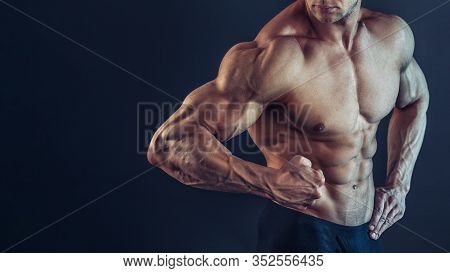 Unrecognizable Strong Athletic Sexy Muscular Man Poising , Showing Biceps And Delts On Black Backgro