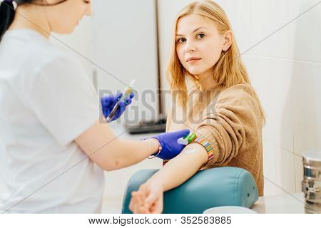 Young Blond Wman In Laboratory In During Blood Research. Unrecognizable Nurse Drawing Blood Sample F