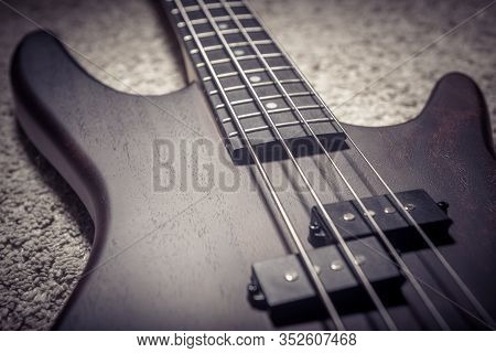 Bass Guitar With Four Strings Closeup. Detail Of Popular Rock Musical Instrument. Close View Of Brow