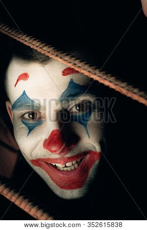 Close-up Portrait Of A Joker Man. Stock Photo Makeup Joker In A Horror Room.