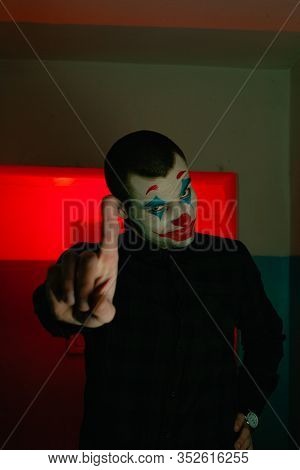 Close-up Portrait Of A Joker Man. Stock Photo Makeup Joker In A Horror Room.