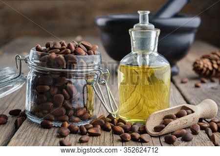 Jar Of Pine Nuts And Pine Nuts Essential Oil Bottle. Black Mortar On Background.