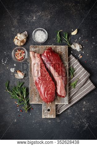 Raw Fresh Steak Sirloin Flap Served With Rosemary, Garlic And On Wooden Cutting Board. Black Angus B