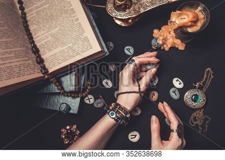 Astrology And Esotericism. The Witch Is Guessing On Runestones.hands Close Up. On A Black Background