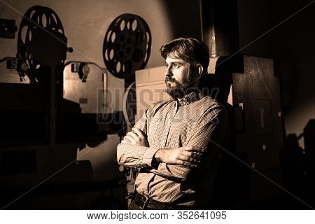 Beautiful Hipster Man Standing Near A Film Projector In The Room Projectionist
