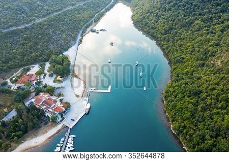 Water Channel Among The Mountains With Houses And A Pier On The Shore. Sailing And Motor Boats Sail 