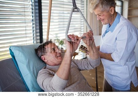 Healthcare Worker Helping Paralysed Senior Patient In Hospital.