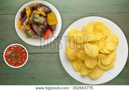 Potato Chips On A White Plate With Vegetarion Salad. Chips On A Green Wooden Background Top View.