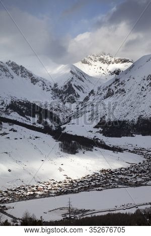 Snowy Ski Slope With Cableways And Town In Mountain Valley At Sunny Winter Evening. Italian Alps. Li