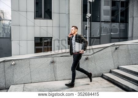 Time Is Running Out. A Young Man In Chic Casual Clothes Runs Up The Stairs To The Business Center Of