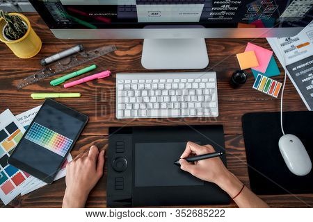 Top View Of A Designer Using Graphic Tablet And Working With Computer While Sitting At His Workplace