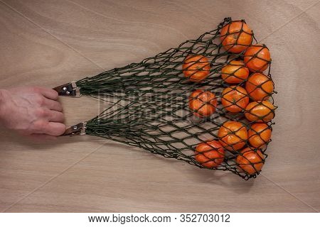 Mandarins In Green Net Bag Zero Waste Concept Lay On Wooden Table