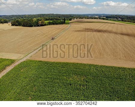 Aerial View Of Tractor On The Road Next To Dry Agriculture Field. Walloon Brabant, Belgium.
