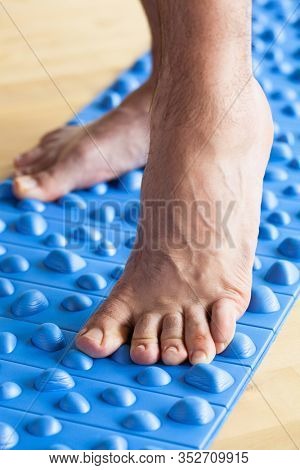 man doing flatfoot correction gymnastic exercise walking on massage mat at home