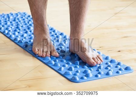 man doing flatfoot correction gymnastic exercise walking on massage mat at home