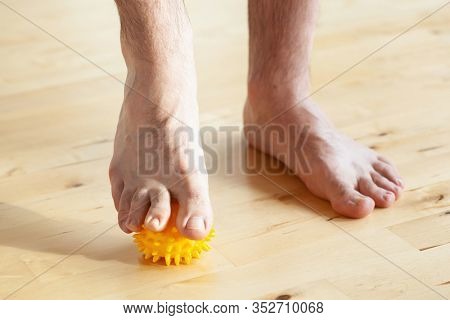 man doing flatfoot correction gymnastic exercise using massage ball at home