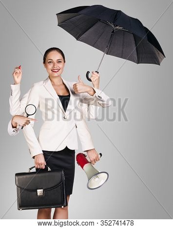 Young Business Woman Multitasking With Different Staff In Hands. Over Gray Background.