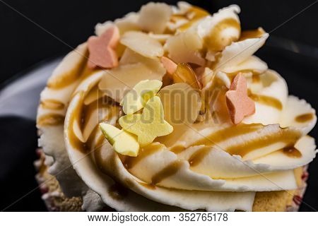 Closeup Of Cupcake Buttercream Topping Drizzled With Caramel And Colorful Butterfly Shaped Sprinkles