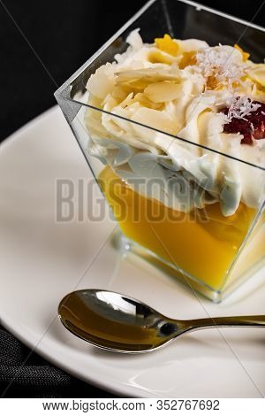 Individual Portion Of Two Layer Dessert In Trapezoid Glass On White Saucer With Teaspoon, Cropped